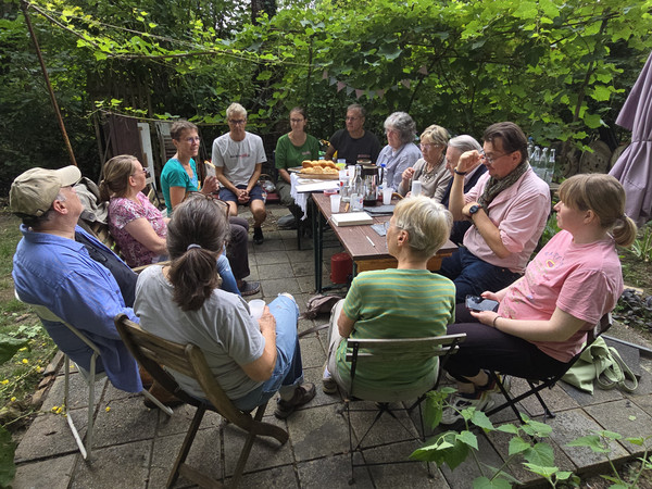 Gesprächsgruppe sitzt um einen Tisch auf der Terrasse 